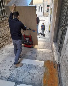 Transport d'un meuble lourd sur un escalier extérieur en pierre