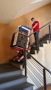 Un homme transporte la photocopieuse dans les escaliers avec le chariot d'escalier Domino